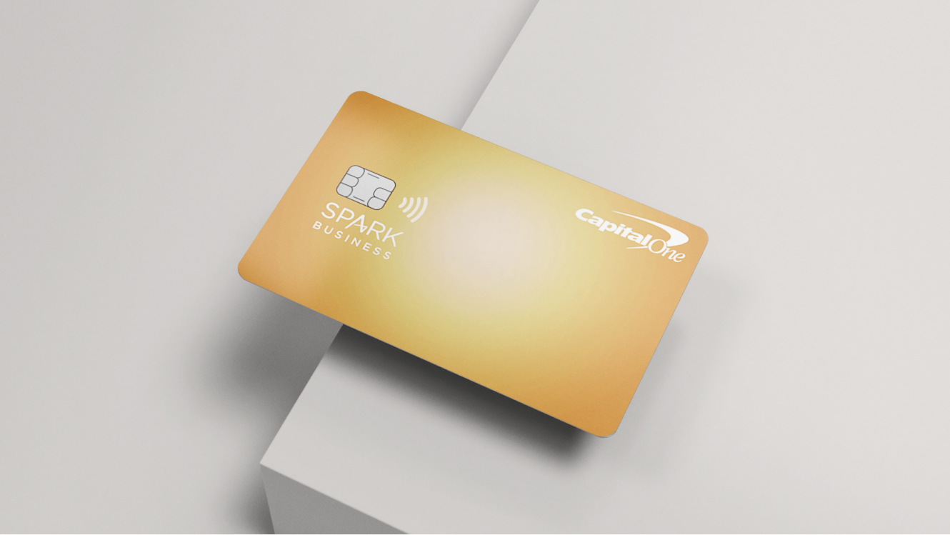 A Capital One Spark 1% Classic credit card on the edge of a grey table.